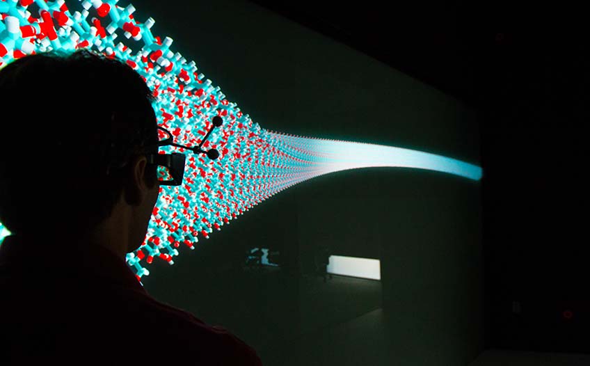 A man in 3D goggles looks at a large energy technology visualization in a dark room