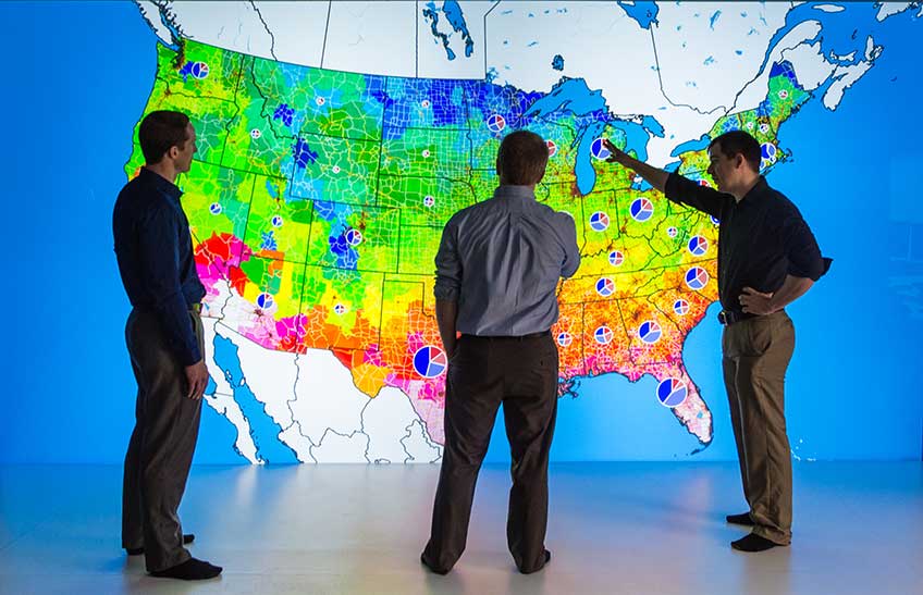 Three people looking a large U.S. map