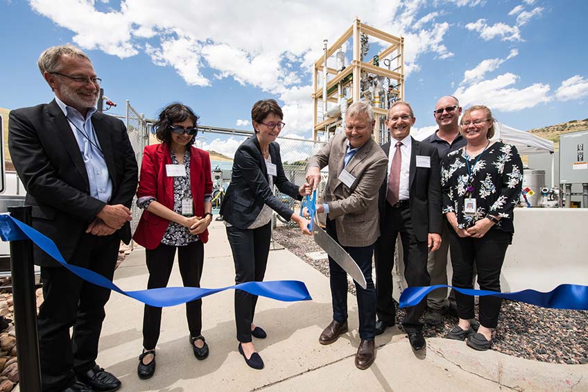 A group of people cut a ribbon to dedicate a bioreactor at NREL.