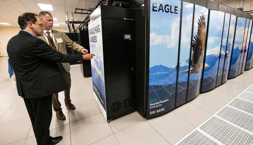 Photo of two men pointing at a supercomputer in a data center.
