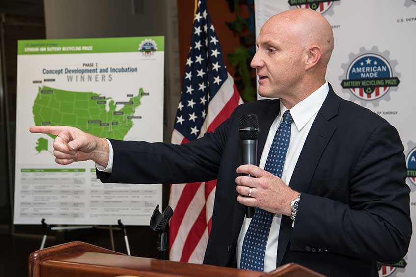 Man in suit with microphone pointing off camera.