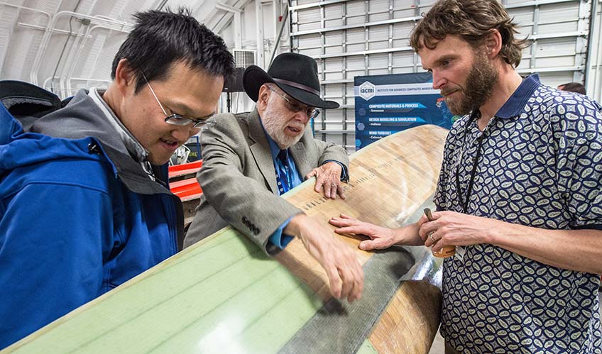 Three men examine a turbine blade manufactured in the CoMET.