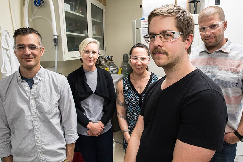 A group of scientists display samples of the alga.