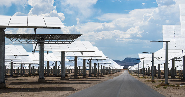 Rows of mirrored heliostats in front of a mountain range.