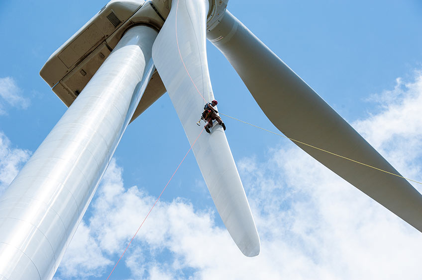 A man rappels off the side of a wind turbine. 