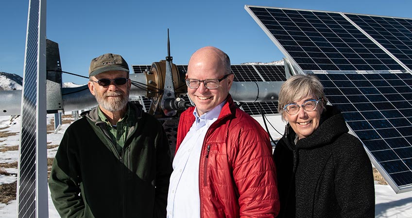 Photo of three people standing in front of a PV array