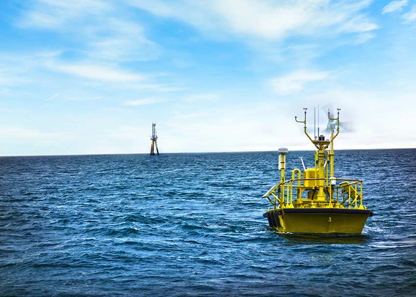 A yellow buoy floats on coastal blue waters with cloud streaked skies overhead. 