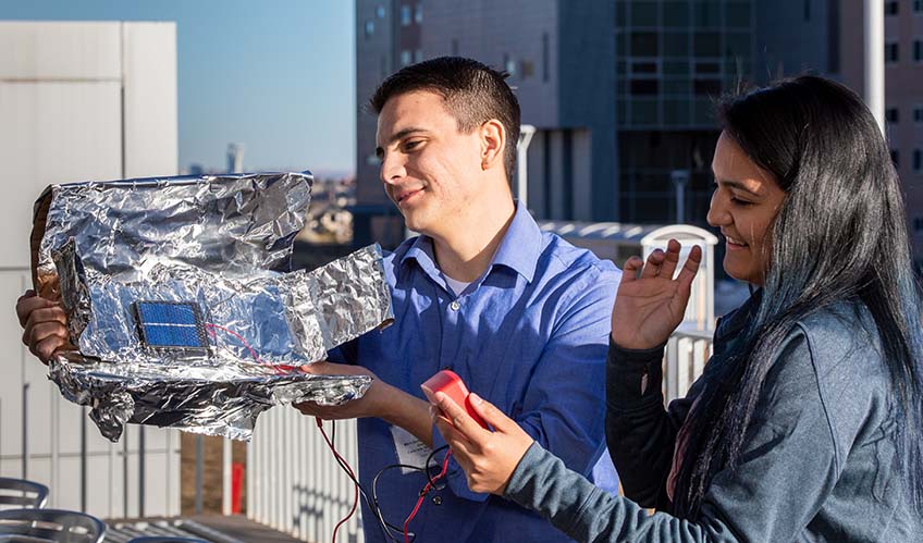 A man and a woman hold an aluminum device outdoors.