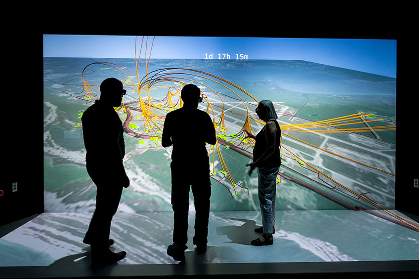 Three researchers look at a 3D visualization screen