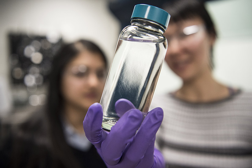 Two researchers hold up a bottle of high-performance diesel biofuel