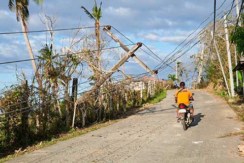 A person rides a motorbike on a street with a damaged power line.