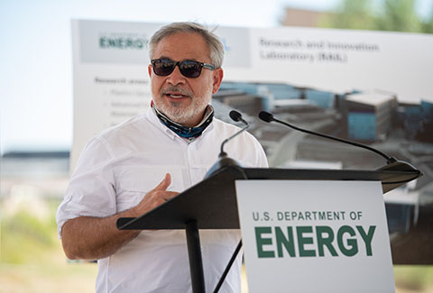 A man speaking at a podium labeled with Department of Energy