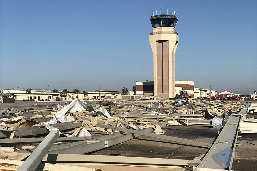 Debris from destroyed aircraft hangars is scattered around a control tower.