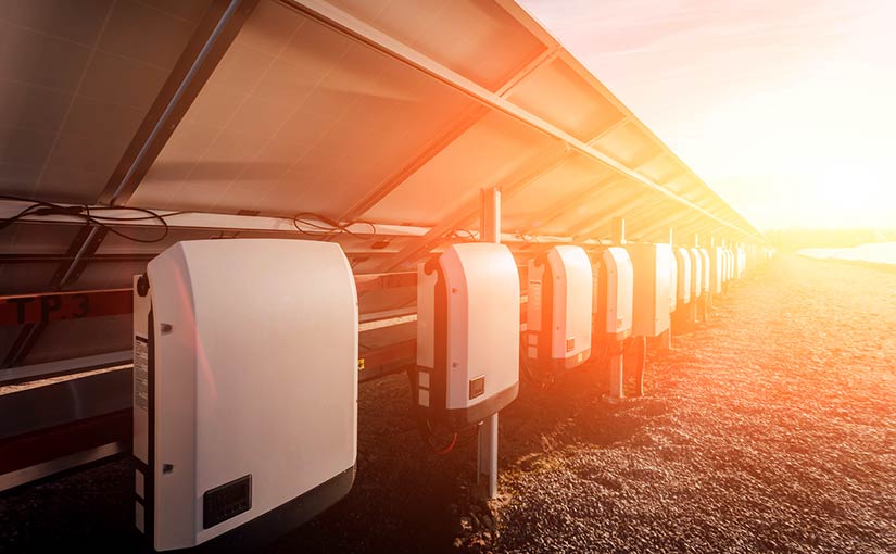 Photo of a group of solar photovoltaic panels and solar inverters in bright sunlight.