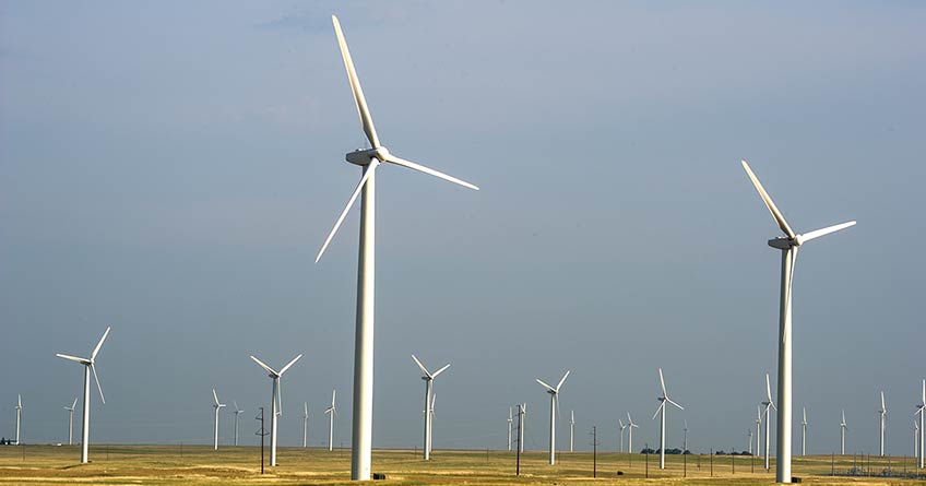 A field of turbines with an overcast sky. 