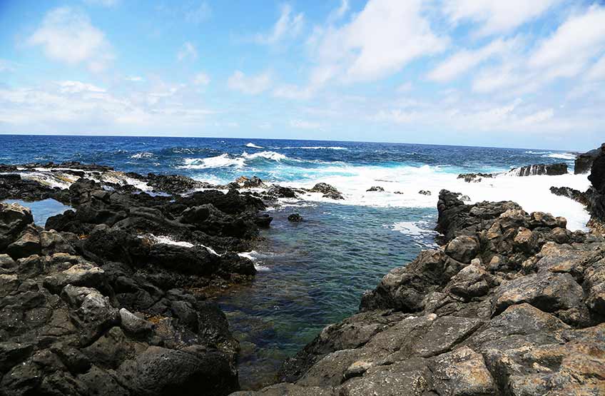 Ocean waves crash onto a rocky beach during the day. 