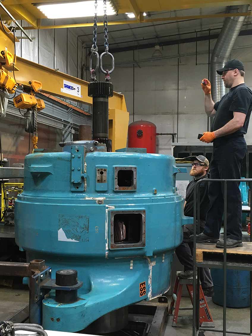 Wind plant operators disassemble and inspect a General Electric Transportation System wind turbine gearbox for damage.