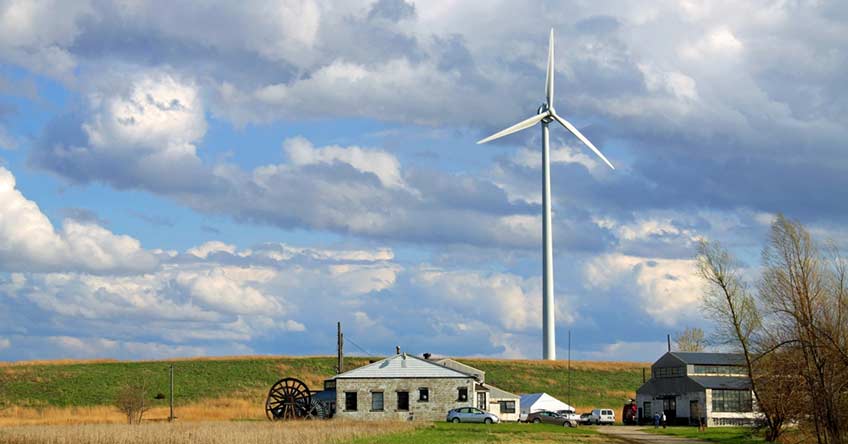 A single wind turbine rises over a rural landscape.