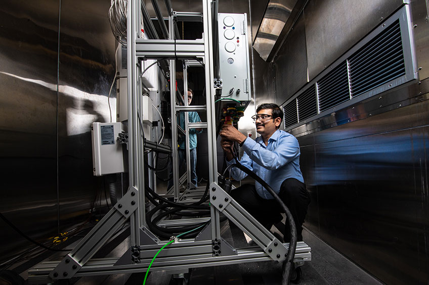 Photo of two men wearing safety glasses testing residential batteries.