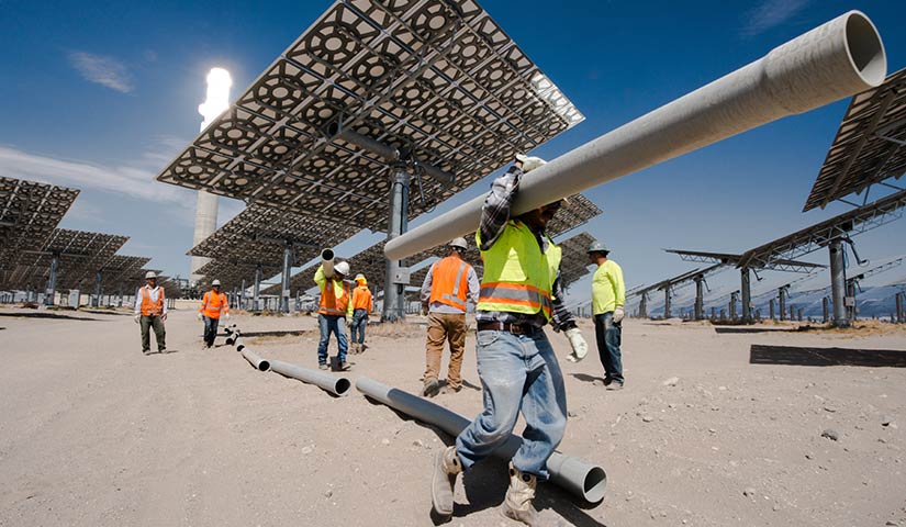 Workers outside carrying pipes