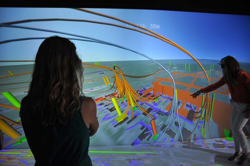 Photo of two women looking at a 3D visualization of data.