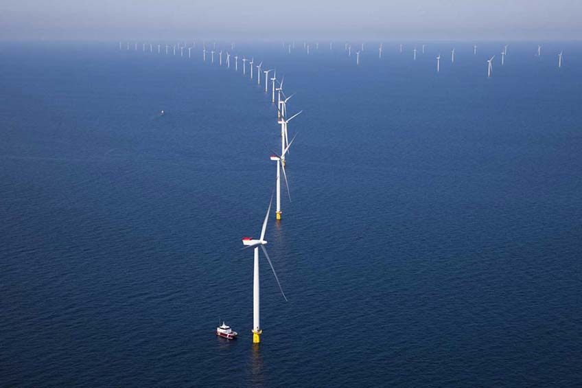 Two boats navigate the waters around an offshore wind farm.  