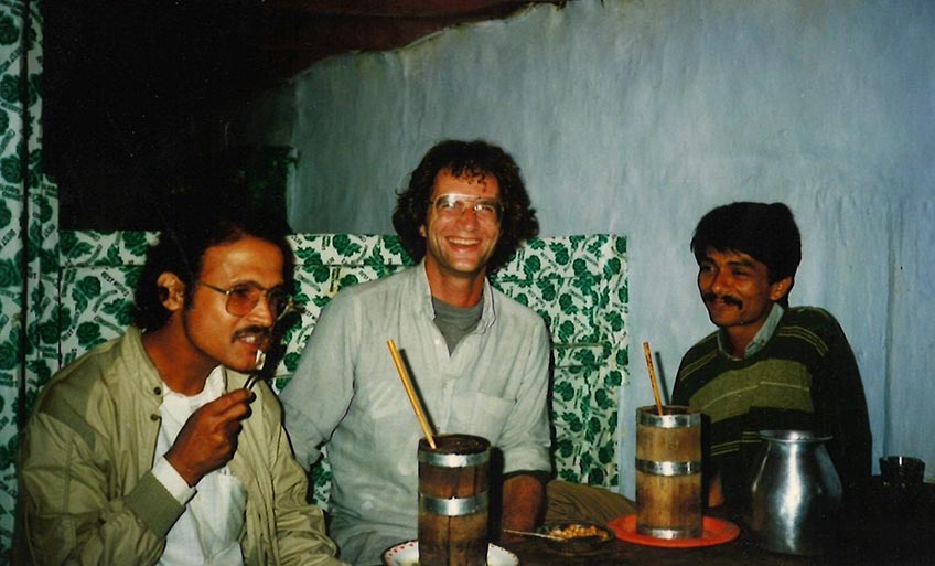 Three men sitting at a table smiling. 