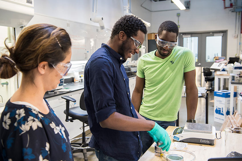 Researchers and intern at workstation in a lab setting