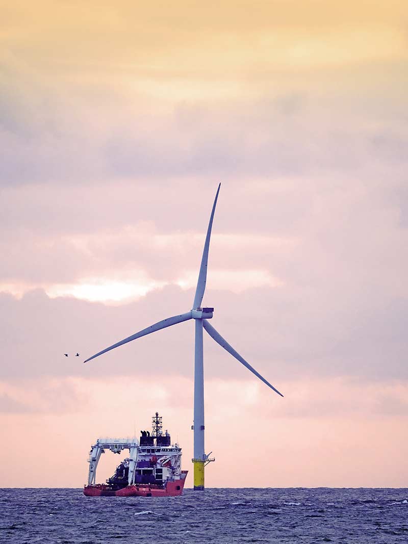 A seafaring vessel outfitted to move offshore wind turbines floats near a turbine in the North Sea.