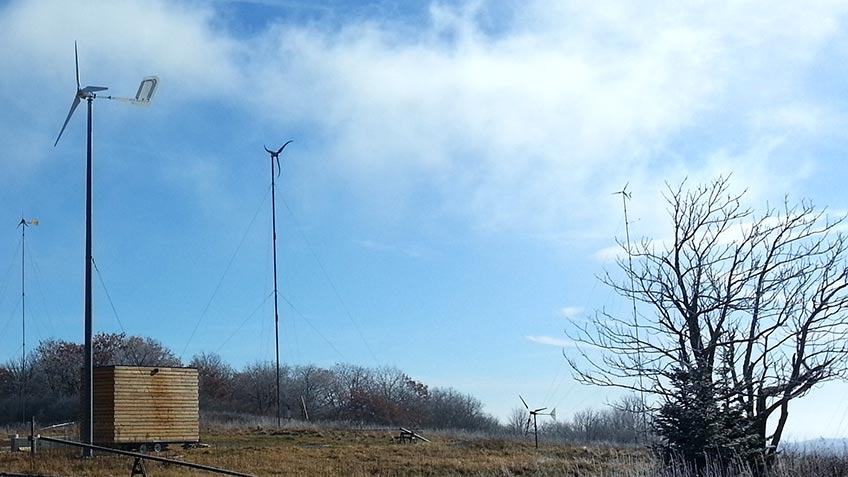 Five distinct distributed wind turbines standing in a field during the day.