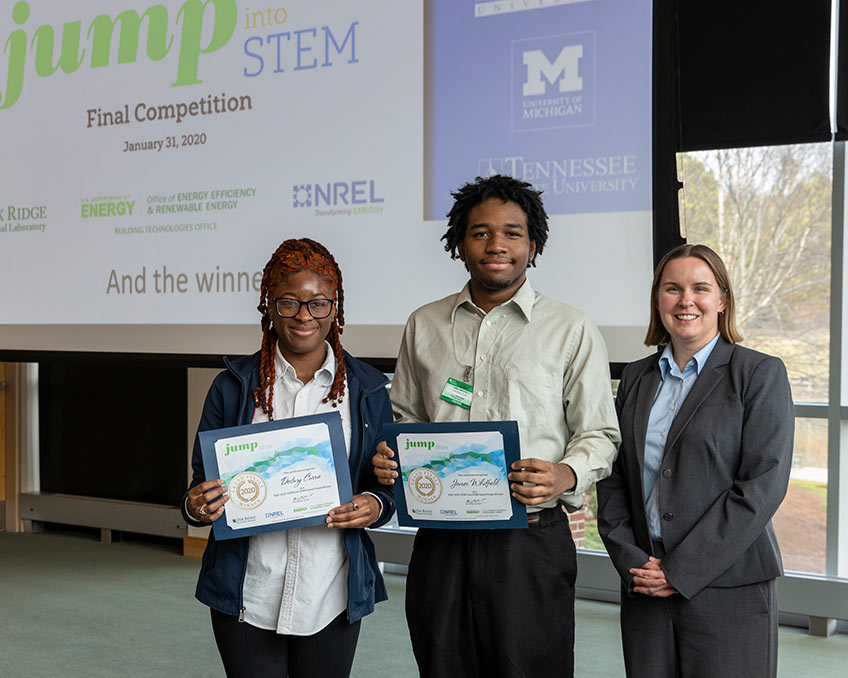 Three people standing and displaying certificate awards.