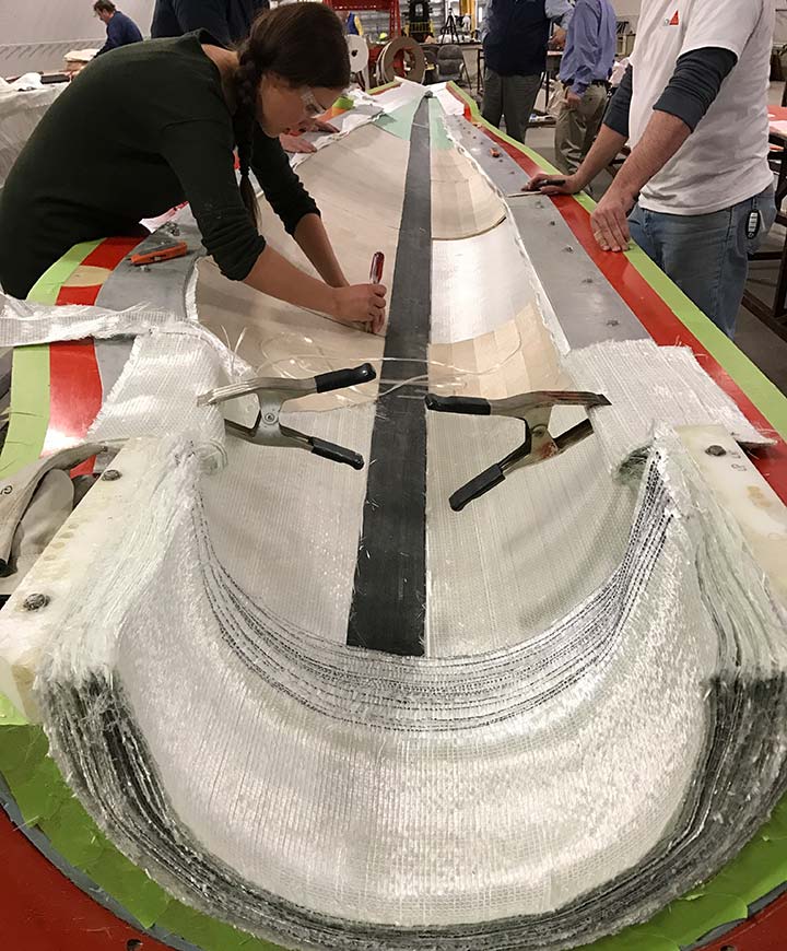 NREL researchers lay thermoplastic materials on a wind turbine blade.