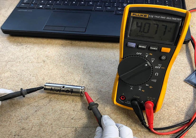 Photo of a battery being tested by a voltometer