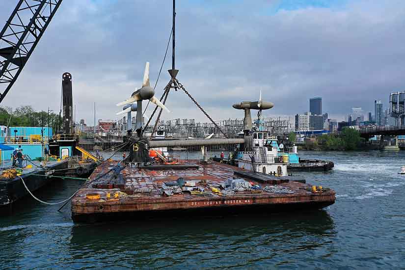 A barge with underwater turbine blades floats in the water