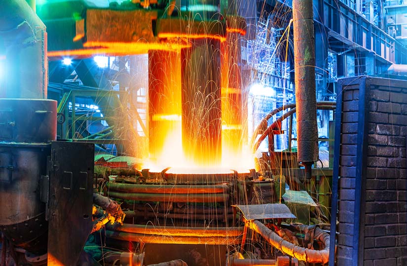 Photo of an electric arc furnace heating up charged material. The furnace looks hot and sparks are flying. This is an energy process to heat the materials.