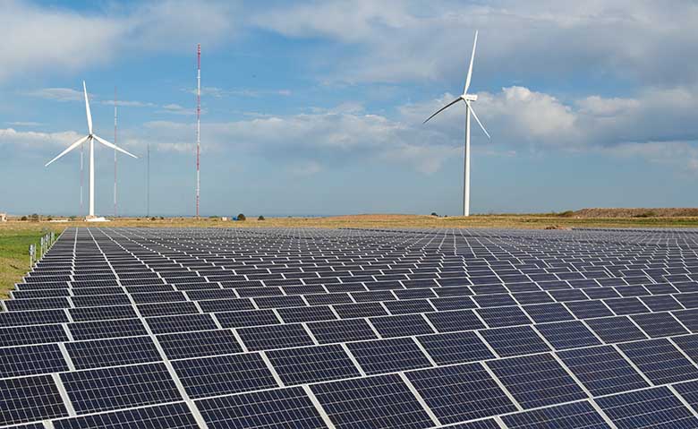 Wind turbines loom behind a solar array