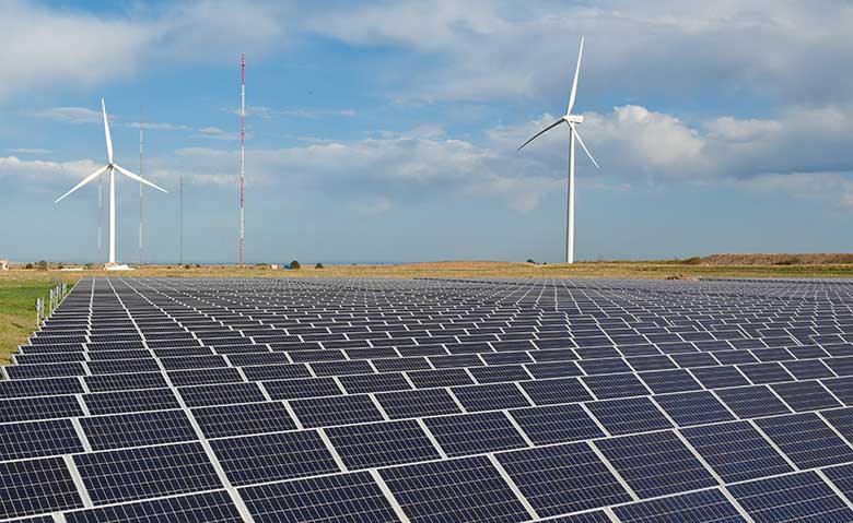 A wind turbine looms behind a photovoltaic array.