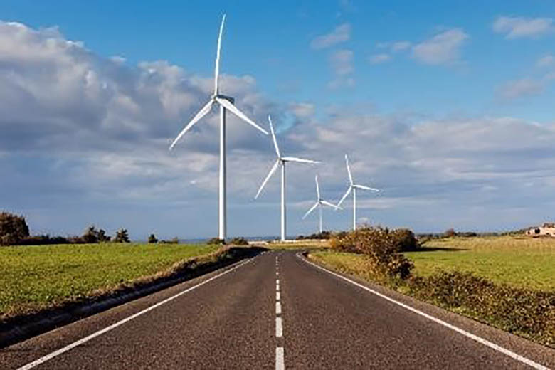 A highway leading to a group of wind turbines.