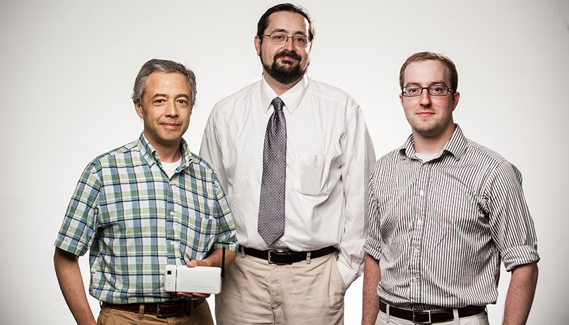 Three men standing and smiling.