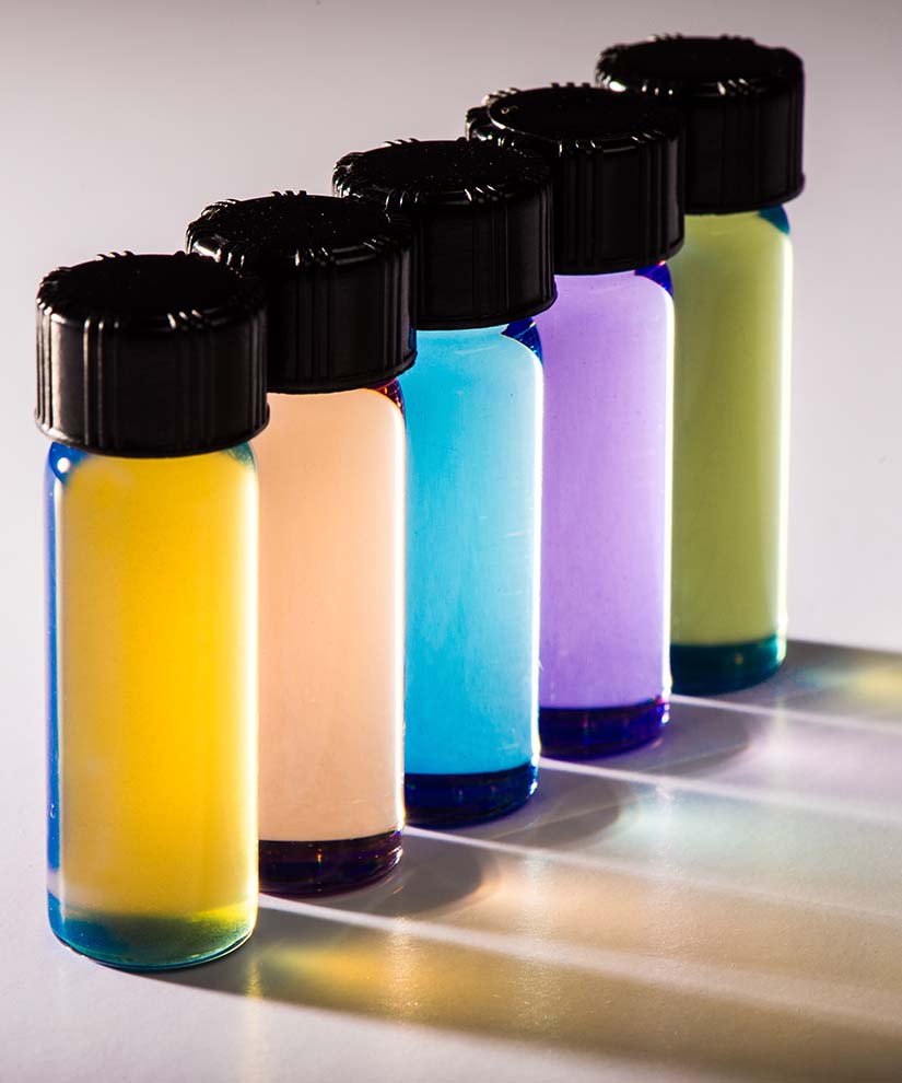 5 vials stacked in a line contain different, vibrantly colored solutions.