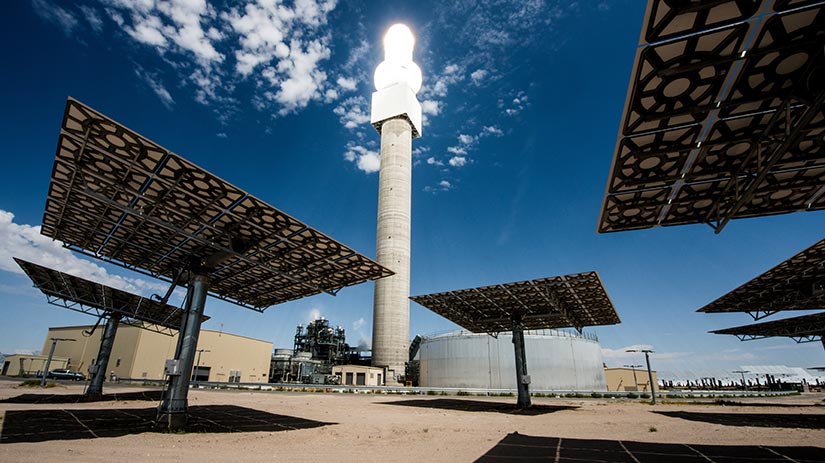 Photo of solar panels in the foreground with a large illuminated power tower in the background. The facility in Nevada represents the future of concentrating solar power.