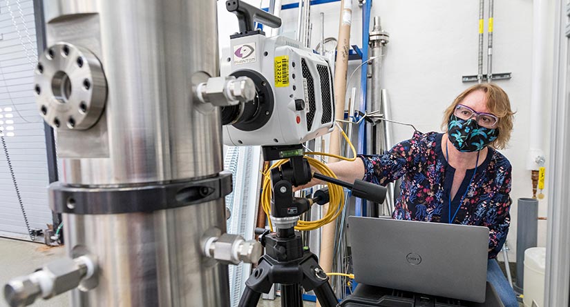 A woman looking at metal machinery. 