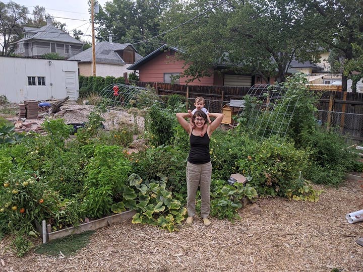 Picture of Alex in her garden with her young son on her shoulders.