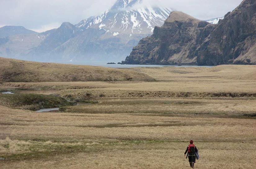 A woman walking towards mountains.