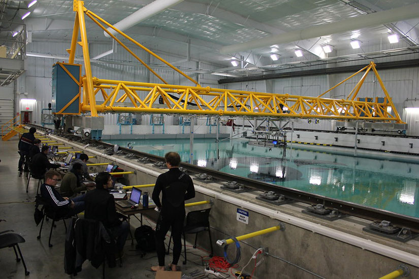 A group of people stand on the side of a pool while conducting tank tests.