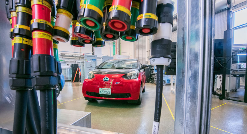 Image of an electric vehicle inside a laboratory. High-powered charging cables are in the foreground.