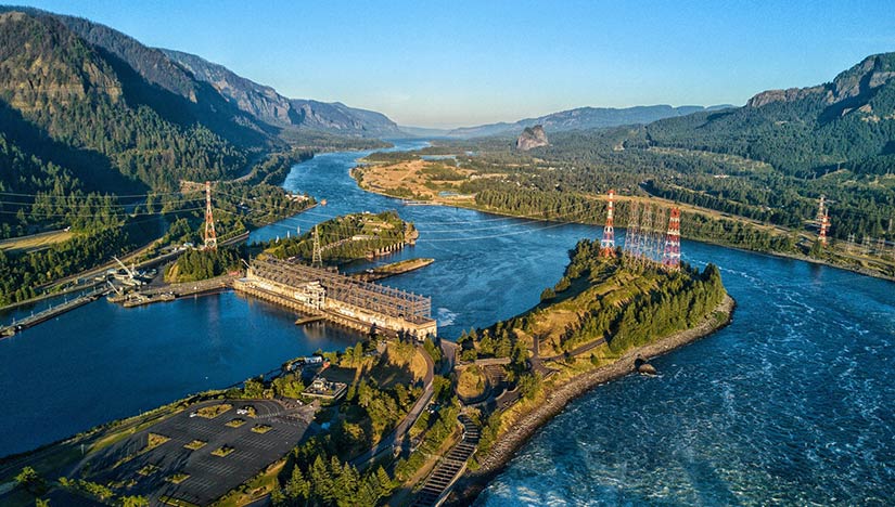 Aerial photo of a hydropower plant with transmission lines on a river.