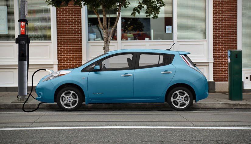 An electric vehicle parked on the street and plugged into a streetlight charging station