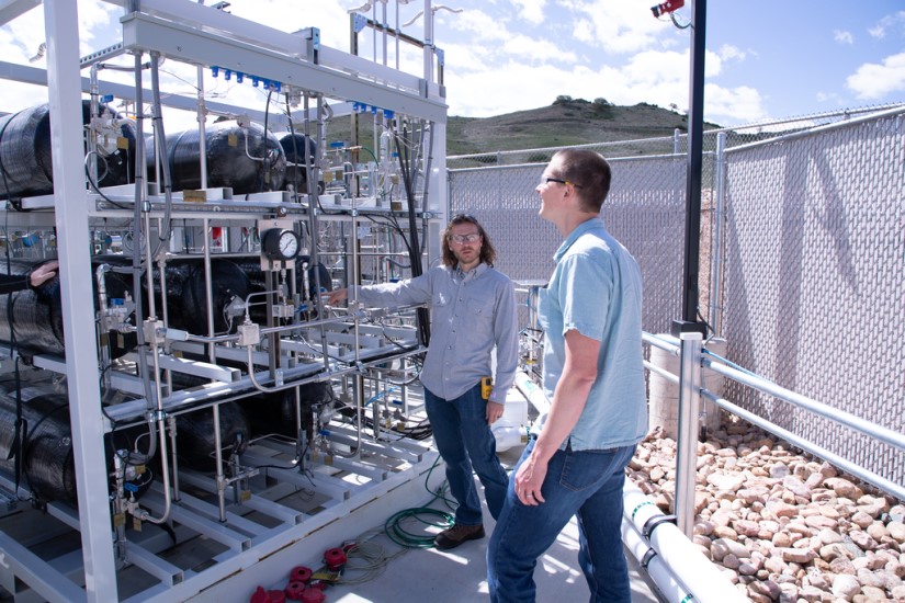 Two researchers stand in front of NREL's heavy-duty hydrogen fueling station. 