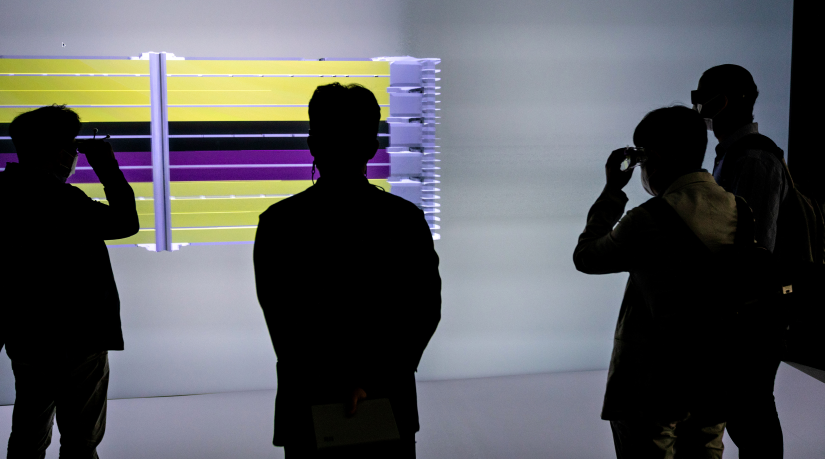 Four silhouettes stand in front of a digital display. 